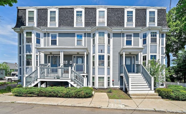 view of front of house featuring stairs, mansard roof, and a shingled roof