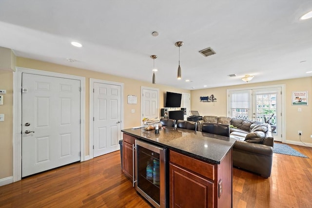 kitchen featuring beverage cooler, dark wood finished floors, baseboards, decorative light fixtures, and dark stone countertops