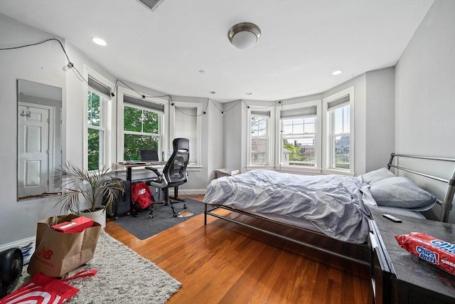 bedroom featuring wood finished floors, an office area, baseboards, and recessed lighting