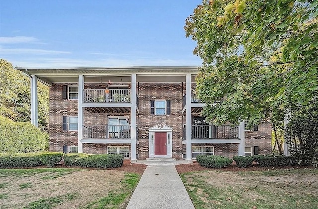 view of front of house featuring brick siding and a balcony