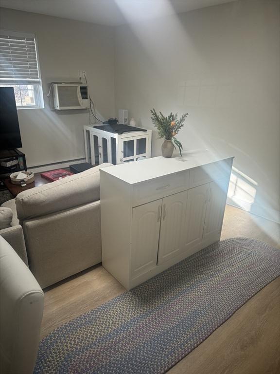 interior space featuring light wood-style floors, baseboard heating, and a wall unit AC