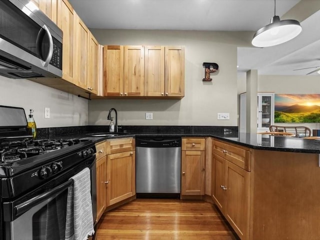 29 Chelmsford St Unit 2, Boston, MA 02122 - kitchen featuring stainless steel appliances, a peninsula, light wood finished floors, dark stone counters, and pendant lighting
