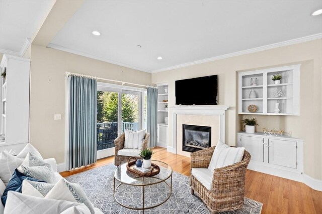 living area with a fireplace, light wood-style floors, and built in features