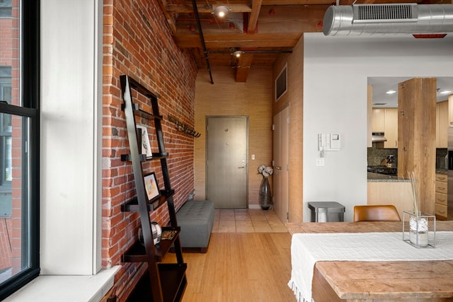 hall featuring beamed ceiling, brick wall, wood ceiling, and light hardwood / wood-style floors