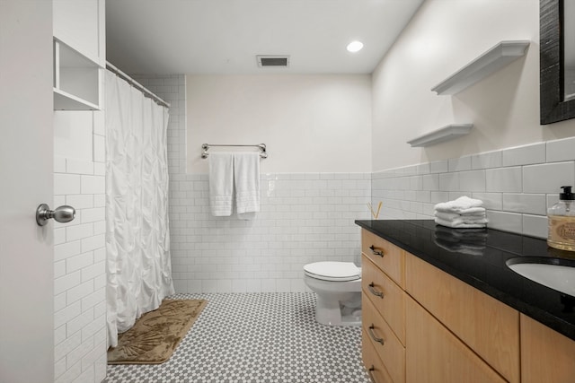 bathroom featuring a shower with shower curtain, toilet, tile walls, vanity, and tile patterned flooring