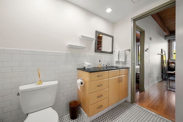 bathroom featuring toilet, vanity, and tile walls