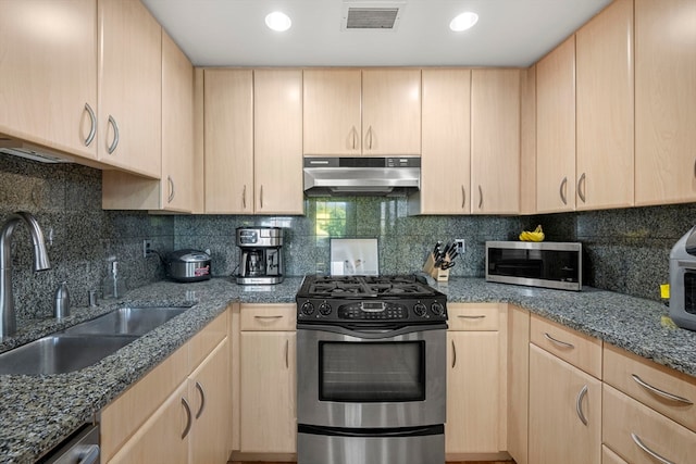 kitchen with appliances with stainless steel finishes, sink, and light brown cabinetry