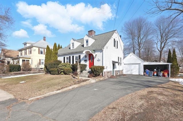 view of front of property with an outbuilding, roof with shingles, a chimney, a carport, and aphalt driveway