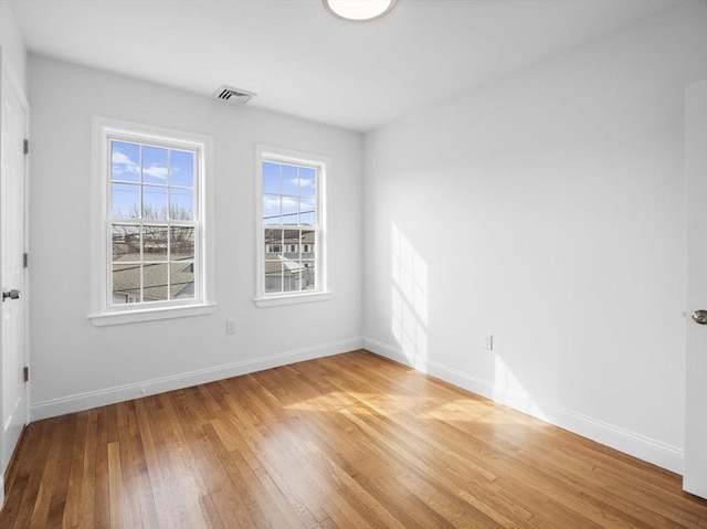 spare room with visible vents, baseboards, and hardwood / wood-style flooring