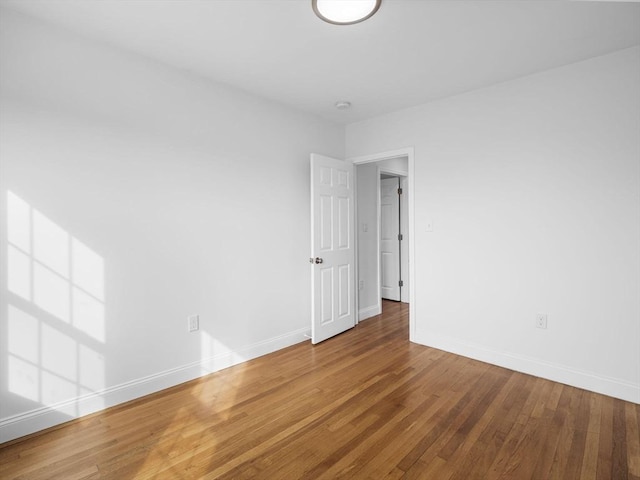 spare room with baseboards and hardwood / wood-style flooring