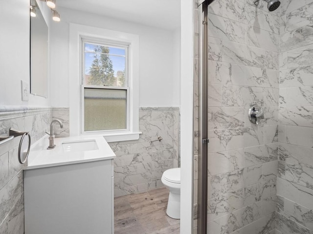 full bathroom featuring a shower stall, wainscoting, tile walls, and vanity