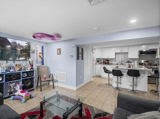 living area featuring light tile patterned floors, visible vents, and baseboards