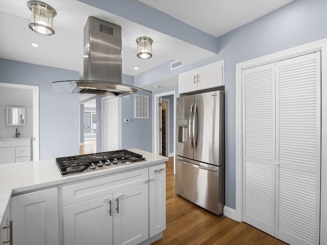 kitchen with island range hood, dark wood finished floors, stainless steel appliances, light countertops, and white cabinetry