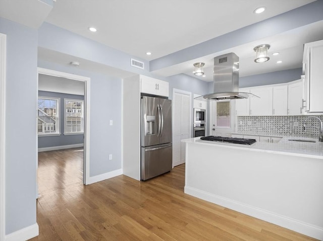 kitchen featuring island range hood, a sink, white cabinetry, light countertops, and appliances with stainless steel finishes