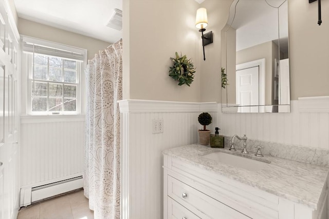 bathroom featuring vanity, a baseboard heating unit, tile patterned flooring, and a wainscoted wall