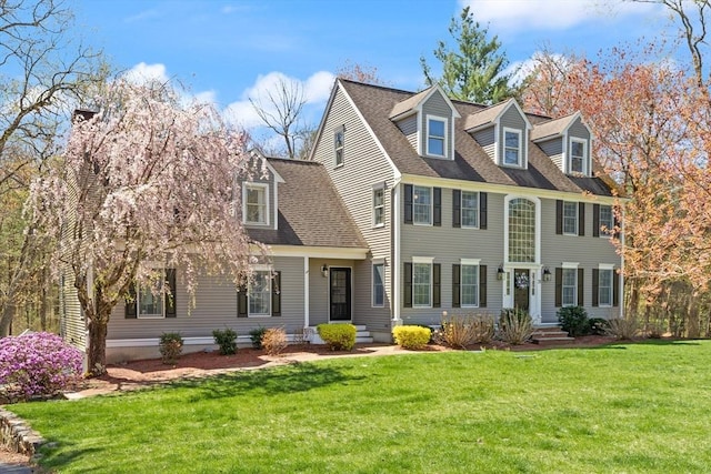 view of front facade with a shingled roof and a front yard