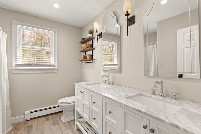 full bath with toilet, a baseboard heating unit, a sink, and wood finished floors