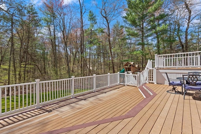 wooden deck with outdoor dining area and a playground