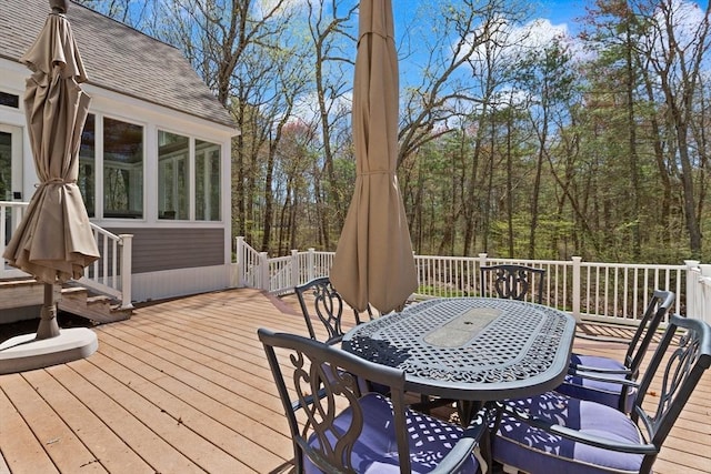 wooden terrace with outdoor dining space and a sunroom