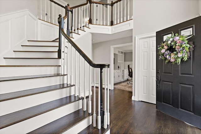 foyer featuring stairs, a towering ceiling, and dark wood-type flooring