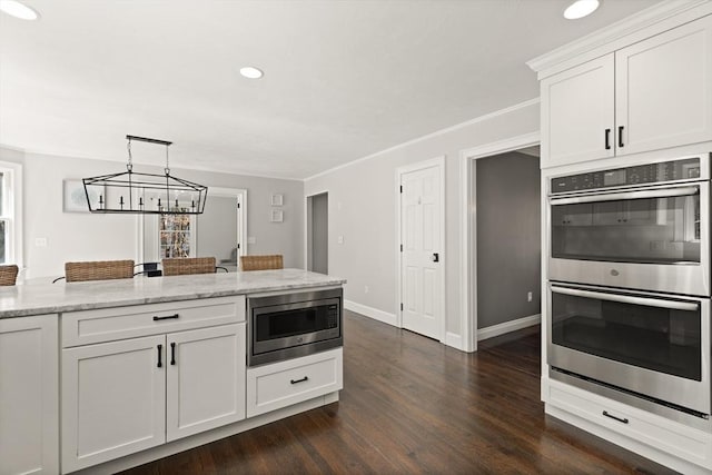 kitchen featuring dark wood-style flooring, appliances with stainless steel finishes, light stone counters, a chandelier, and white cabinetry