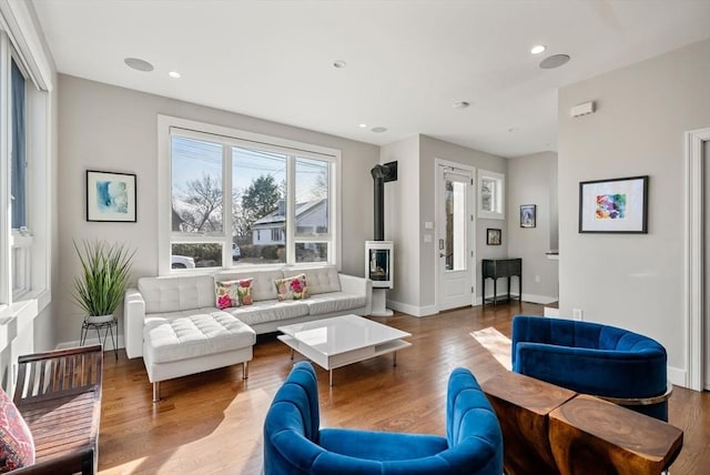 living area featuring a wood stove, recessed lighting, and wood finished floors