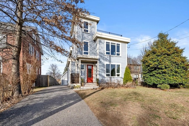 view of front of property featuring driveway, a front lawn, and fence