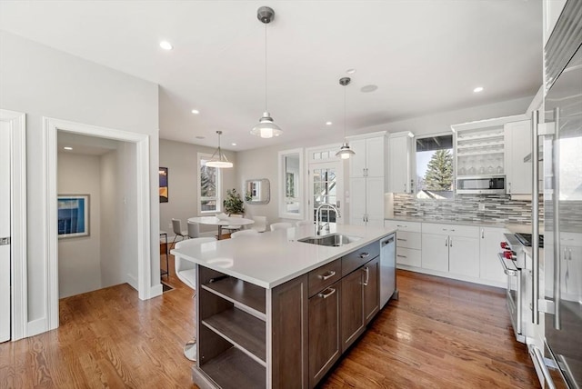 kitchen featuring high quality appliances, open shelves, a sink, dark brown cabinetry, and light countertops