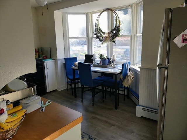 dining area with dark hardwood / wood-style floors, a healthy amount of sunlight, and a baseboard heating unit