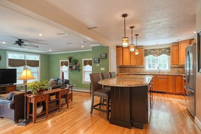 59 Davis St, Northborough, MA 01532 - kitchen with open floor plan, light wood-type flooring, baseboard heating, light stone countertops, and ornamental molding