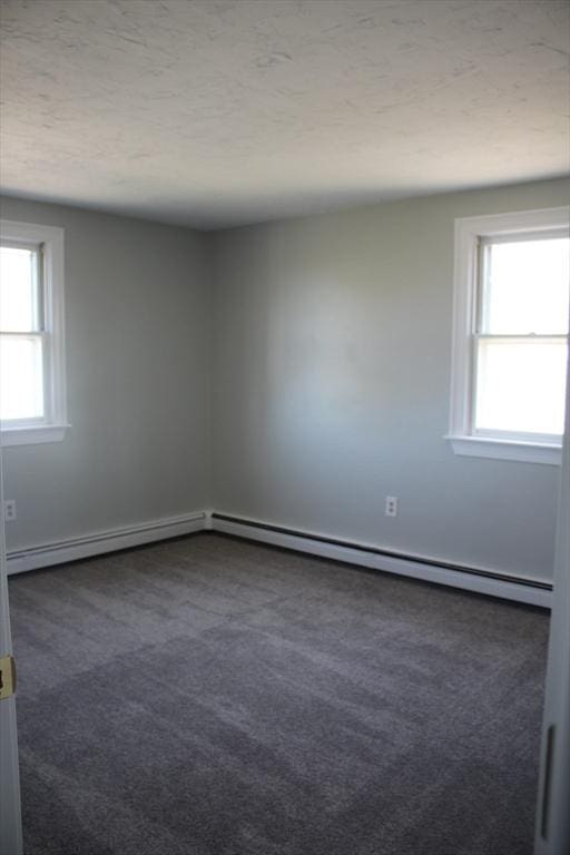 11 Skyview Ln, Woburn, MA 01801 - empty room with baseboard heating, plenty of natural light, dark carpet, and a baseboard radiator
