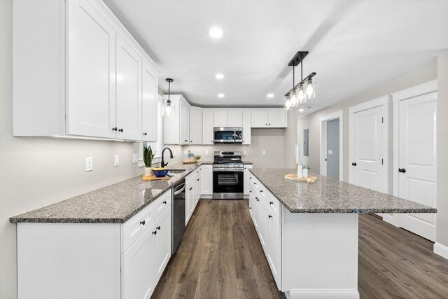 kitchen with a kitchen island, stainless steel appliances, sink, and white cabinetry