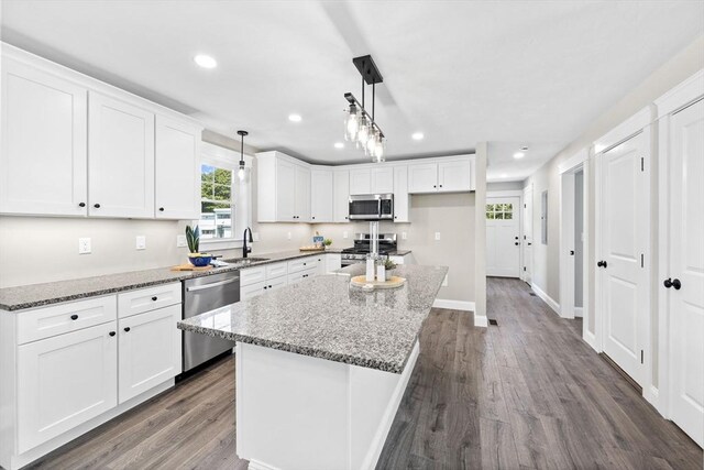 kitchen featuring hanging light fixtures, a center island, appliances with stainless steel finishes, and white cabinets