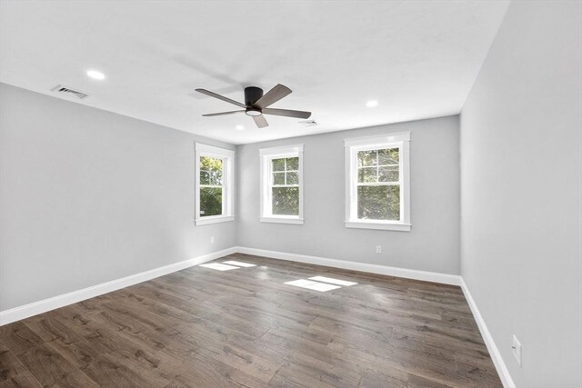 empty room featuring ceiling fan, dark hardwood / wood-style floors, and a healthy amount of sunlight