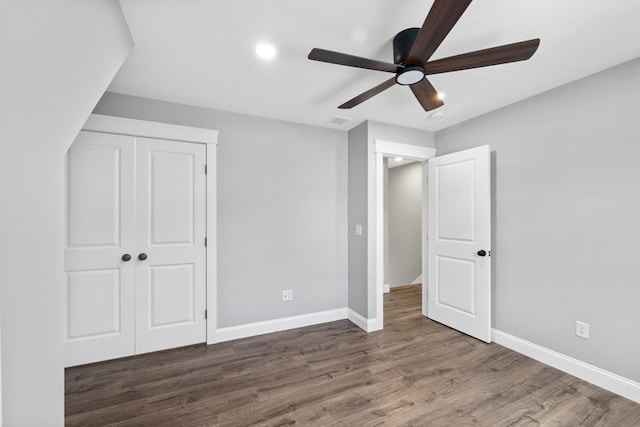 unfurnished bedroom with dark wood-type flooring, ceiling fan, and a closet