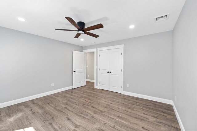 unfurnished bedroom featuring wood-type flooring, ceiling fan, and a closet