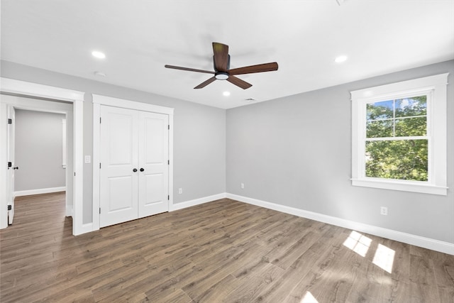 unfurnished bedroom with hardwood / wood-style flooring, ceiling fan, and a closet