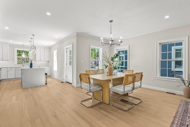 dining area featuring light wood-style floors, ornamental molding, baseboards, and a chandelier
