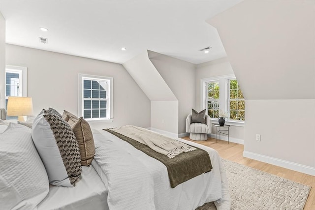 bedroom with visible vents, baseboards, wood finished floors, and vaulted ceiling