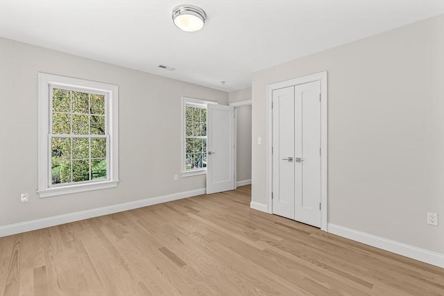 unfurnished bedroom with baseboards, visible vents, light wood-style flooring, and a closet