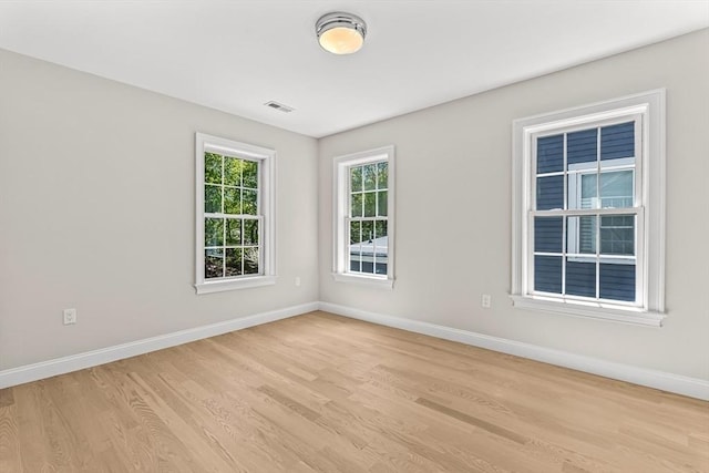 unfurnished room featuring baseboards, light wood-type flooring, and visible vents