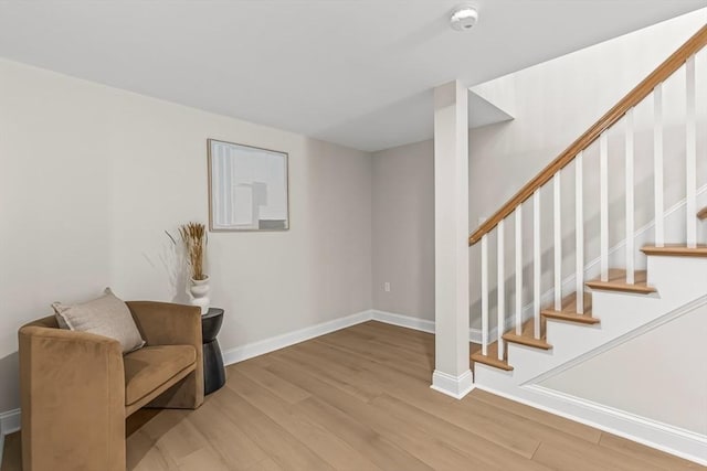 living area featuring baseboards, wood finished floors, and stairway