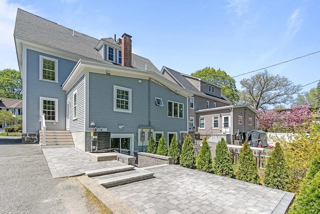 rear view of property with fence, a patio, and a chimney