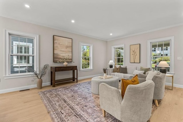 living room featuring light wood-type flooring, ornamental molding, baseboards, and recessed lighting