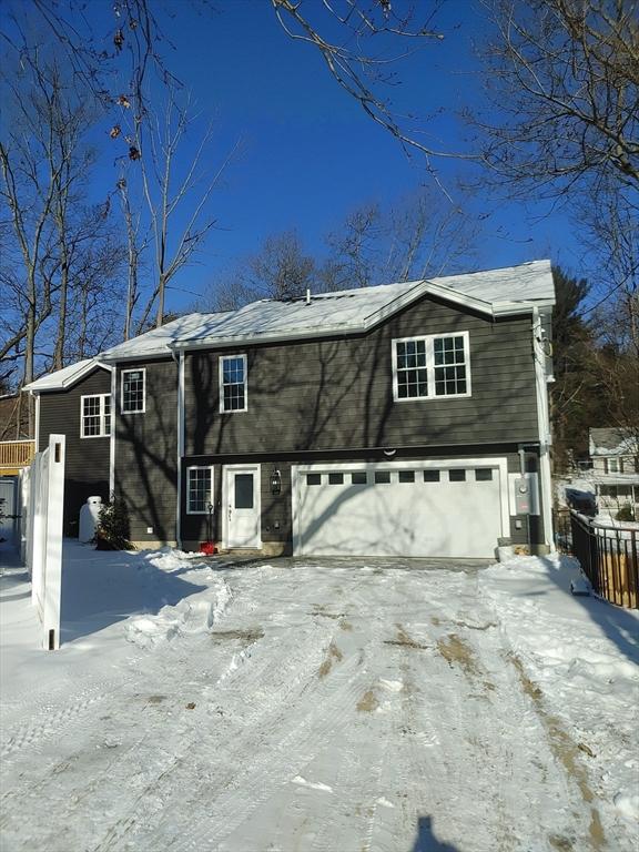 snow covered house with fence and a garage