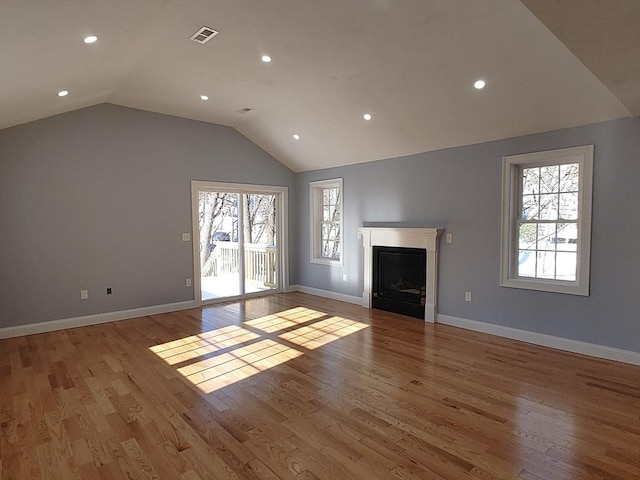 unfurnished living room featuring visible vents, baseboards, vaulted ceiling, a fireplace, and wood finished floors