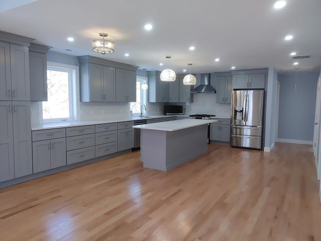 kitchen featuring light countertops, wall chimney range hood, gray cabinetry, and stainless steel appliances