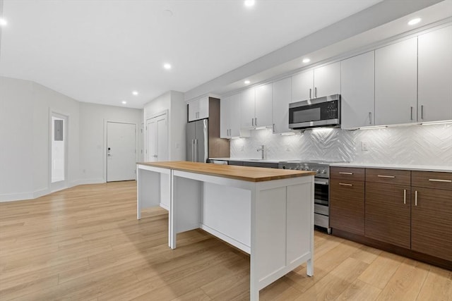 1948-1950 Washington St Unit 3E, Boston, MA 02118 - kitchen featuring high end appliances, butcher block counters, a kitchen island, backsplash, and light wood-style floors