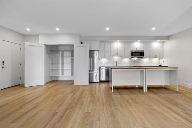1948-1950 Washington St Unit 3E, Boston, MA 02118 - kitchen featuring appliances with stainless steel finishes, white cabinets, light wood-type flooring, tasteful backsplash, and recessed lighting