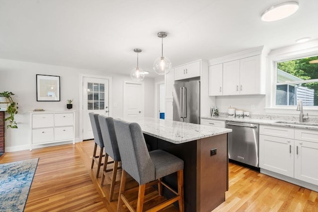 23 Redbird Rd, Wrentham, MA 02093 - kitchen with appliances with stainless steel finishes, a kitchen island, white cabinets, a breakfast bar, and light wood-style flooring